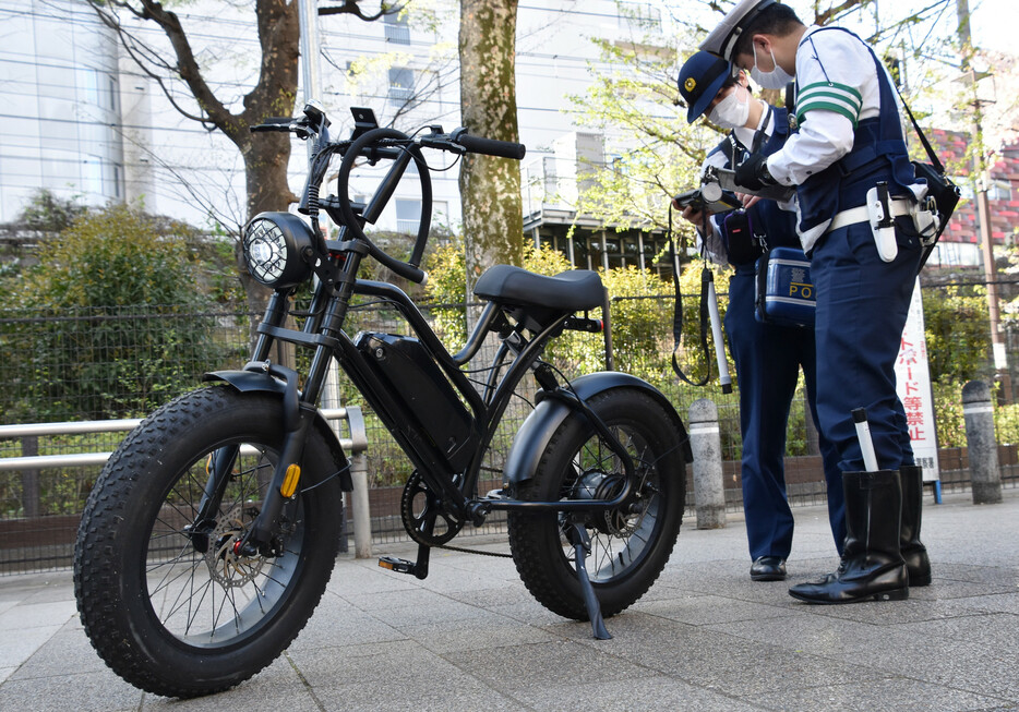 「モペット」を取り締まる警察官。ペダル付き原付き自転車「モペット」は、ペダルをこいで走行してもバイクに分類され、運転にはヘルメットや免許証が必要だ。このルールを明記した改正道交法が１日に施行された。