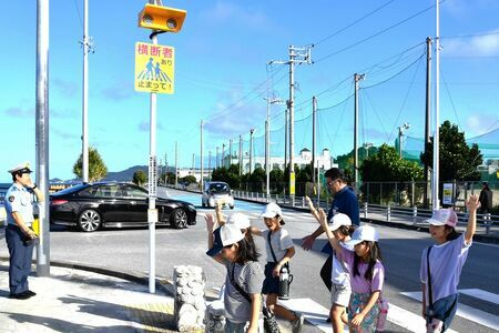 「ゆずるくん」が設置された横断歩道を渡る子どもたち＝１８日、与那原中学校近くの「くじら橋」（提供）