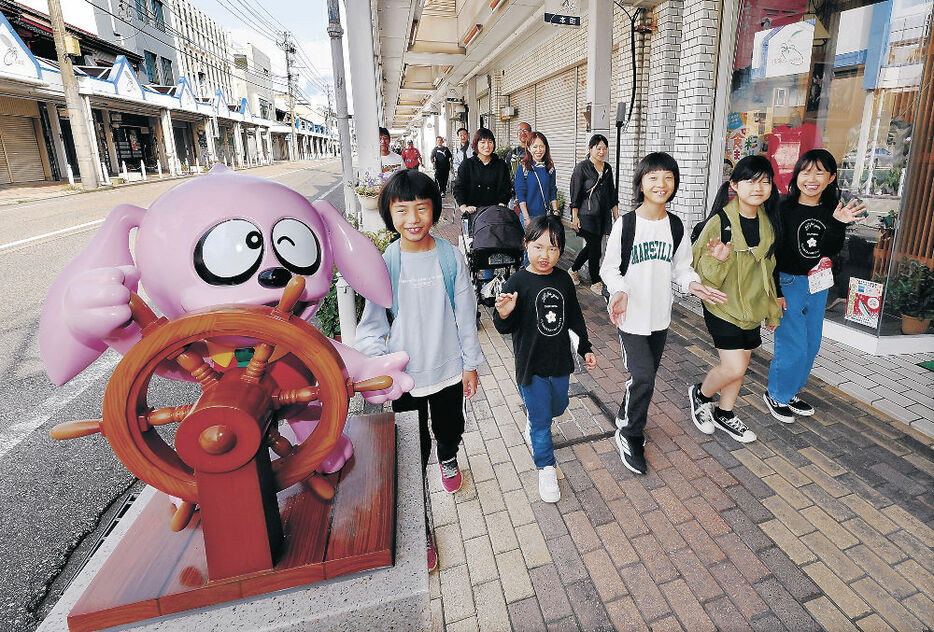 まんがロードに並ぶキャラクターの横を歩く子ども＝氷見市本町