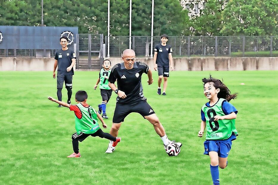 小野さん(中央)とサッカーを楽しむ児童=鳴門市撫養町の鳴門大塚スポーツパーク球技場