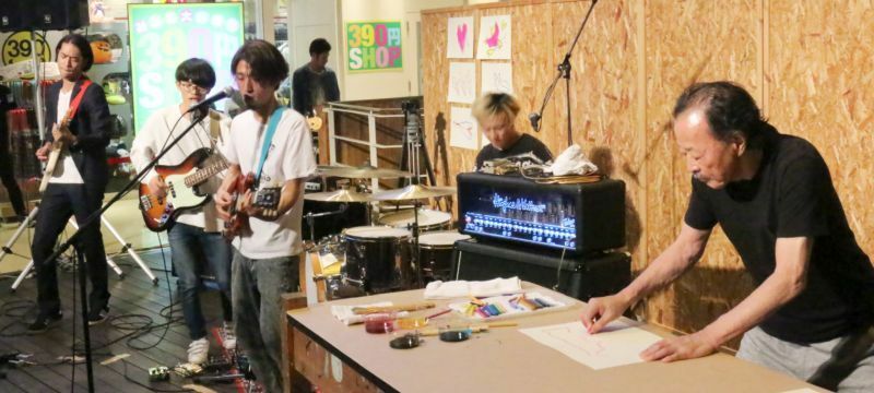 [写真]黒田征太郎（右）がアメリカ村発のバンド「愛はズボーン」の演奏に合わせ作品を制作=28日夜、大阪市中央区で（撮影：柳曽文隆）