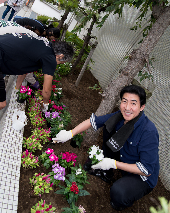 ボランティアの保護者らと花を植える、黒木じゅん（撮影：志和浩司）