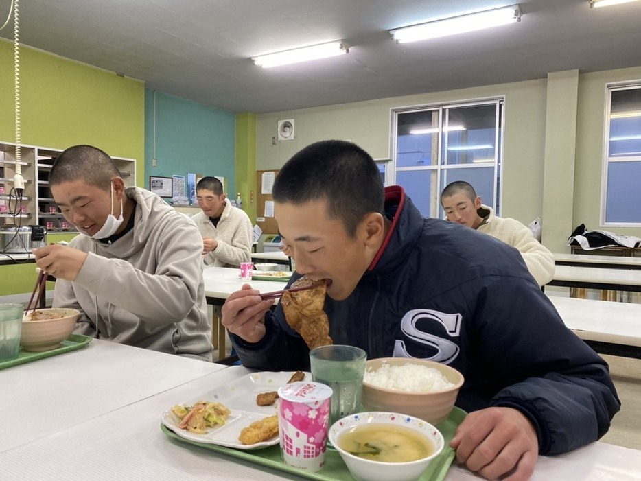 贈られた肉を選手寮の食堂で頰張る広島新庄の選手ら＝北広島町で、同校硬式野球部提供