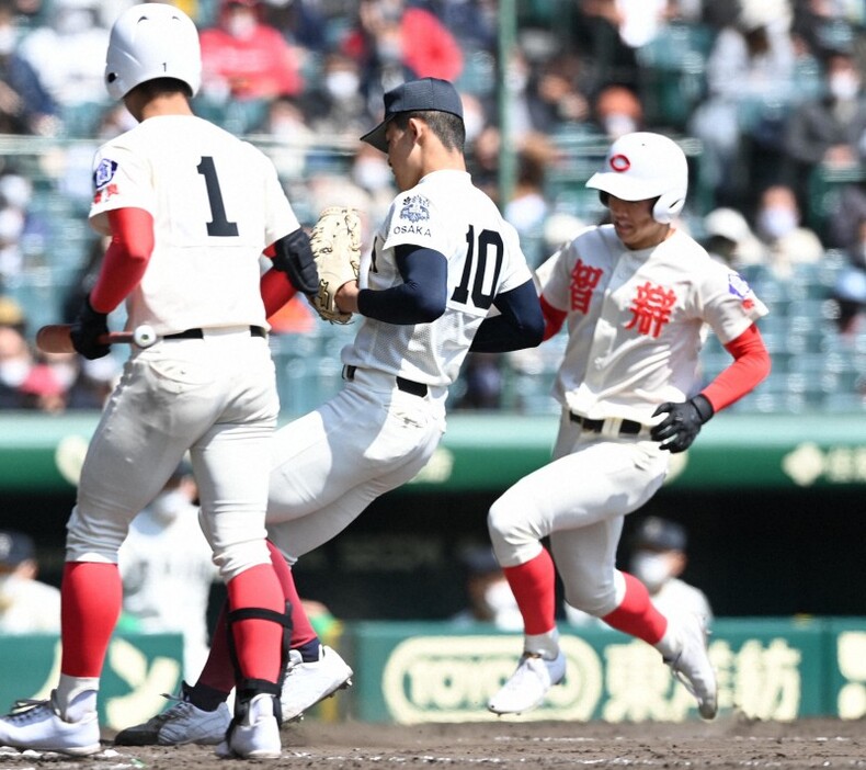 六回裏智弁学園1死三塁、打者西村(左)の時、大阪桐蔭の関戸（中央）の暴投で森田（右）が生還し、7点目＝阪神甲子園球場で2021年3月23日、平川義之撮影