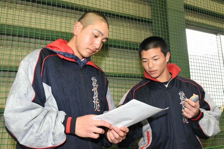 練習試合でつけたスコアを読み返す岩崎登志也選手（左）と阿竹真士朗選手＝福井県敦賀市の敦賀気比高校野球場で、大原翔撮影