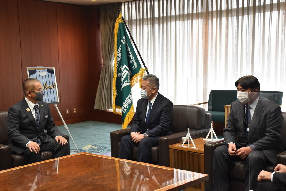 緑のセンバツ旗を前に、相模原市の本村賢太郎市長（左）に大会への決意を述べる東海大相模の土井崇司校長（中央）と門馬敬治監督＝神奈川県相模原市中央区で２０２１年３月４日、宮島麻実撮影