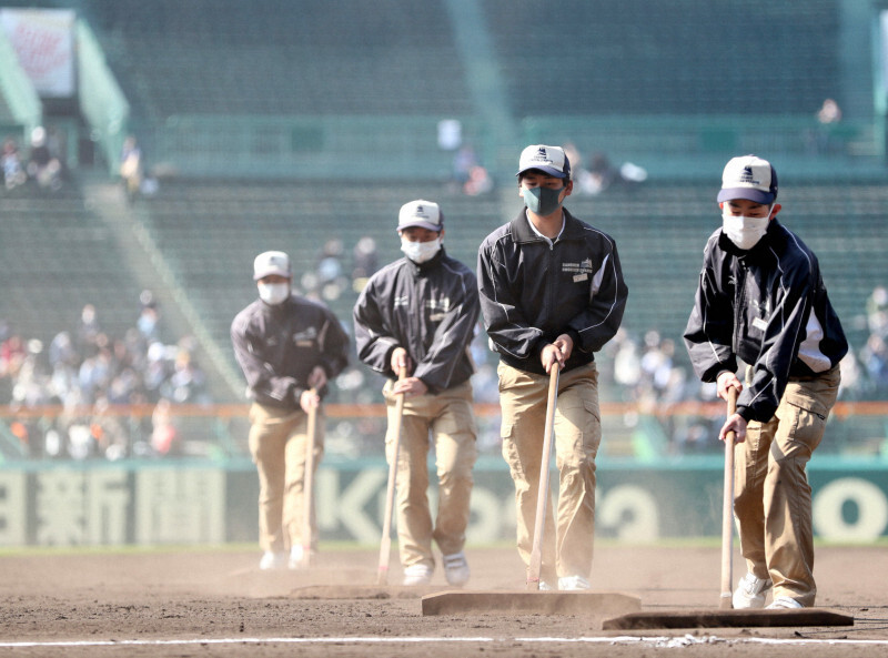 五回終了後に素早くグラウンドを整備する阪神園芸の職員たち＝阪神甲子園球場で2021年3月26日、吉田航太撮影