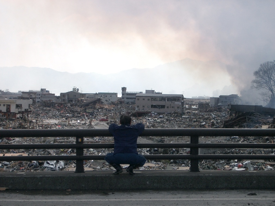 震災直後の町を眺める男性。2011年3月12日（写真集『がんばっぺし大槌』より）