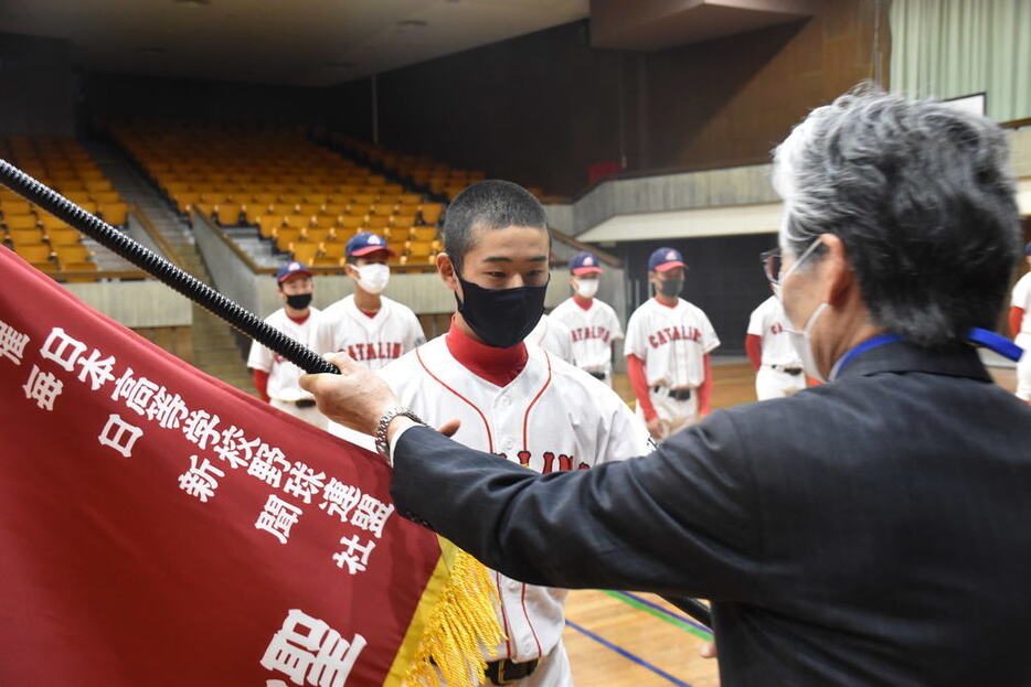 センバツ旗を受け取る聖カタリナ学園の小沢武門主将（中央）＝松山市で２０２１年３月５日午後１時２９分、遠藤龍撮影