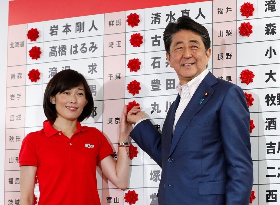 [写真]与党で改選過半数を突破し、笑顔で当確の花をつける安倍晋三首相（右）（ロイター/アフロ）