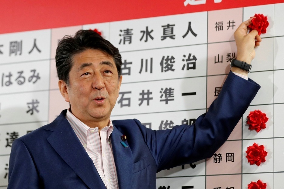 [写真]笑顔で当確の花をつける安倍首相（ロイター/アフロ）