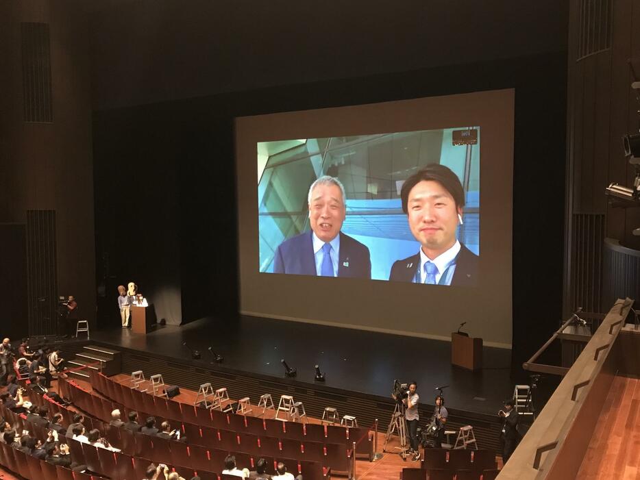 ［写真］パブリックビューイング会場の市民に中継で報告する永藤英機市長(右)ら＝5日午後10時50分ごろ、堺市堺区で