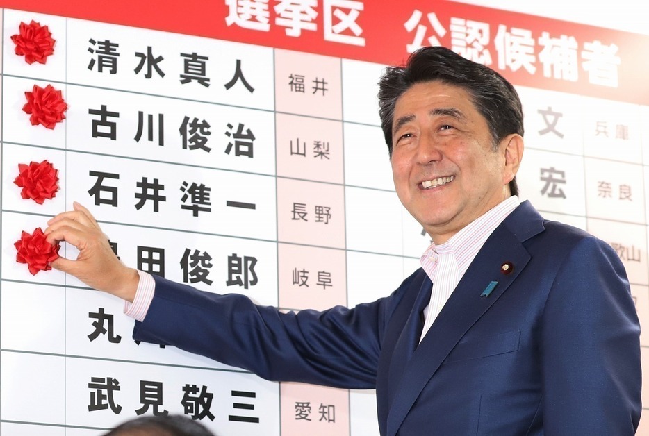 [写真]7月21日に投開票された参院選で、ボードに当確の花をつけて笑顔を見せる安倍氏首相（つのだよしお/アフロ）