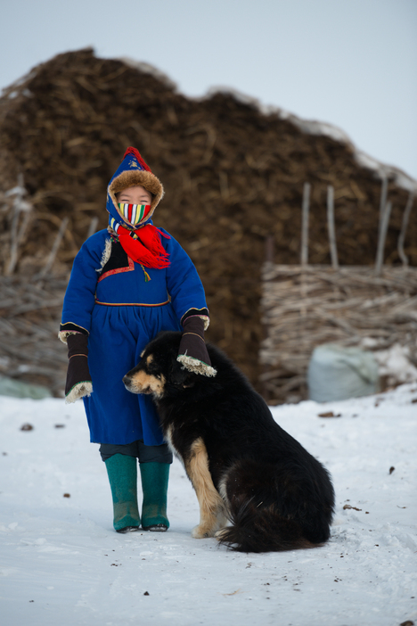 愛犬と一緒に映るブリヤート族の少女はとても無邪気で、民族衣装もきれいだった＝フルンボイル市・エベンキ族自治旗（2018年2月撮影）