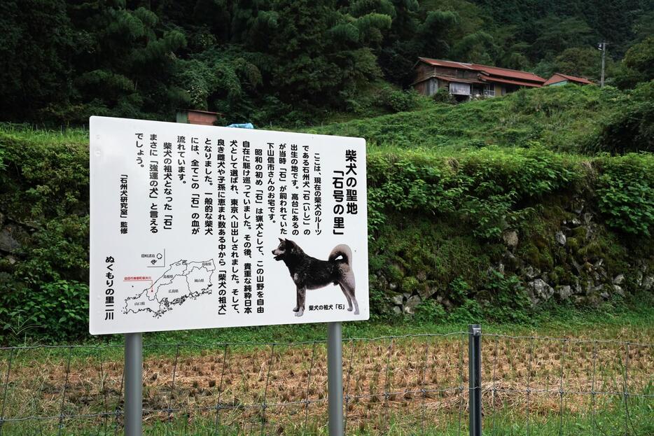 [写真]石号の生家（右上）前に立つ真新しい＜柴犬の聖地「石号の里」＞の看板＝島根県益田市美都町板井川