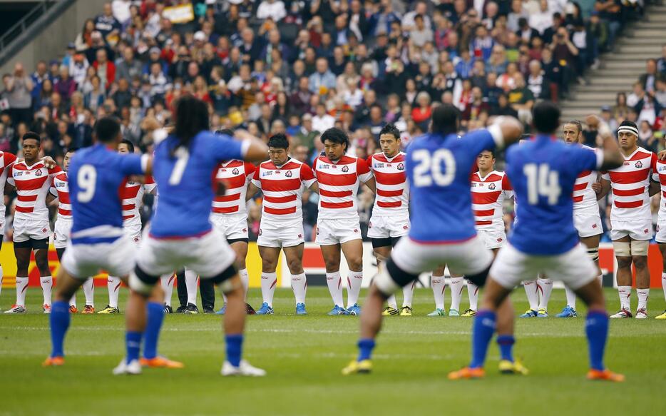 肩を組んでサモア代表の戦いの儀式「シヴァタウ」に向き合う日本代表＝2015年10月3日（写真：ロイター/アフロ）