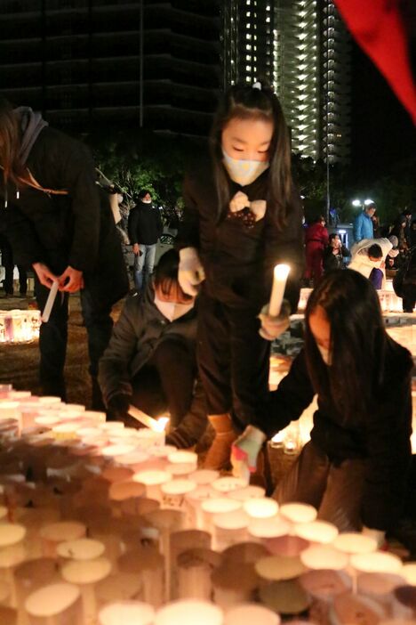 [写真]親から子へ受け継がれる灯火＝17日午前5時半ごろ、神戸市中央区で