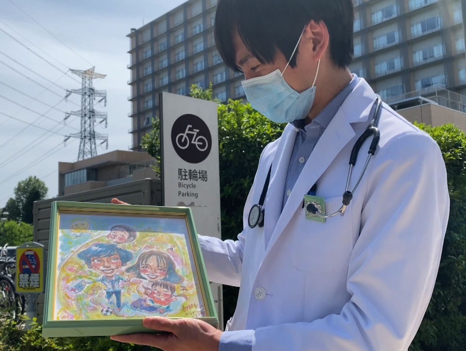 自らと家族の似顔絵を手にする岩浪医師（提供：村岡ケンイチ）