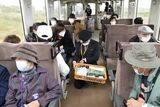 津軽鉄道の車内でお土産品を購入する広島県や大阪府などの団体客。政府の観光支援事業「Go　Toトラベル」の効果も見え始めている＝2020年10月24日