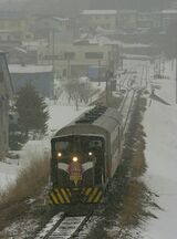 雪が降る中、津軽中里駅（上方）を出発するストーブ列車＝2006年ごろ