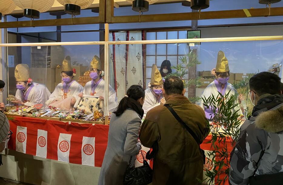 ［写真］本戎を迎えるも人かげがまばらな今宮戎神社。マスク姿の福娘はシート越しに笑顔＝10日午後8時ごろ、大阪市浪速区で