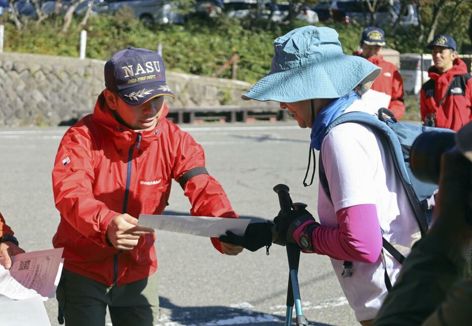 登山客にチラシを配る消防関係者＝13日午前、栃木県那須町