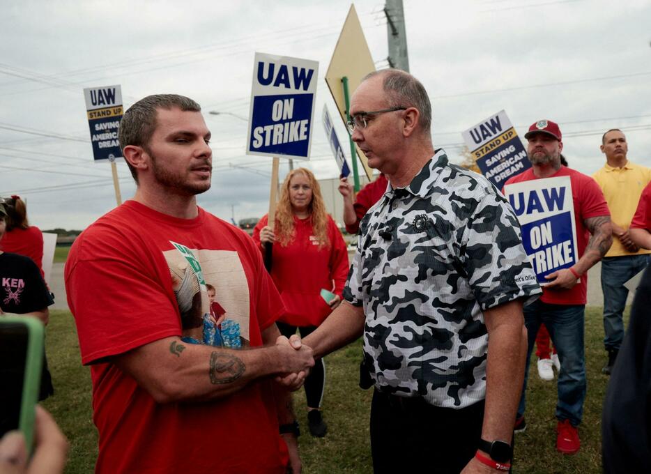 UAWの組合員と握手するフェイン会長（右）＝9月、米ミシガン州（ロイター＝共同）