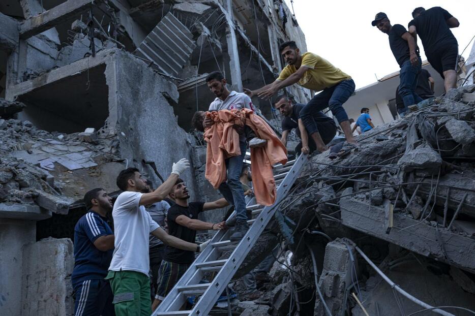 イスラエルによる空爆で破壊された建物のがれきの中から救助される少女＝10日、パレスチナ自治区ガザ（AP＝共同）