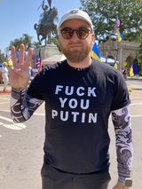 ダンのTシャツには「くたばれプーチン」の文字。三本指でウクライナの国章「三叉戟」を示す（筆者撮影）