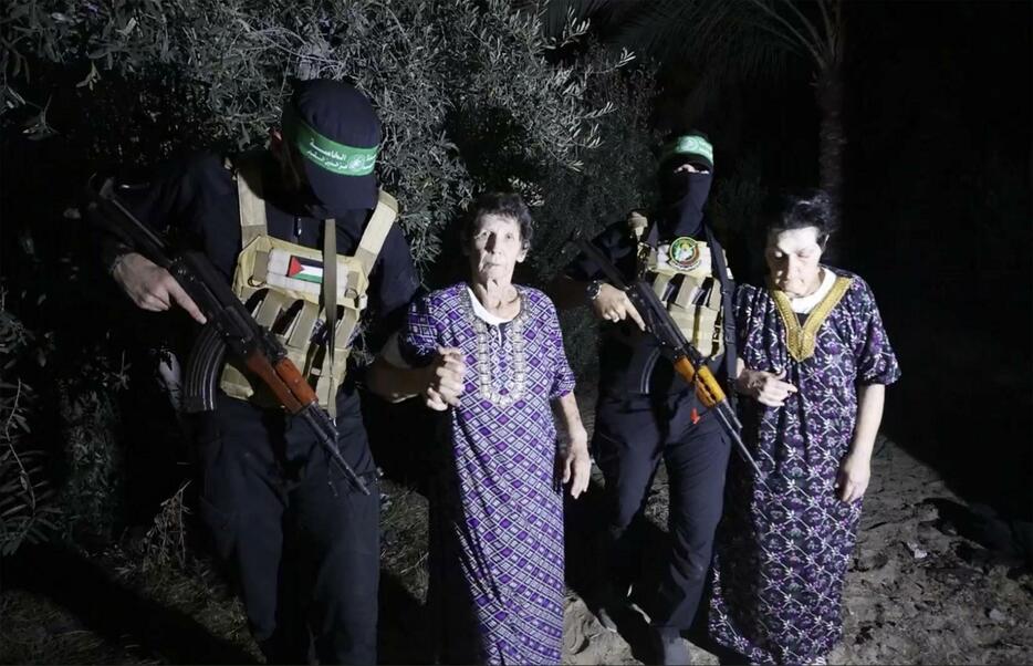 23日、イスラム組織ハマスのメンバーに付き添われ解放される女性2人。ハマスがビデオを公開した（AP＝共同）