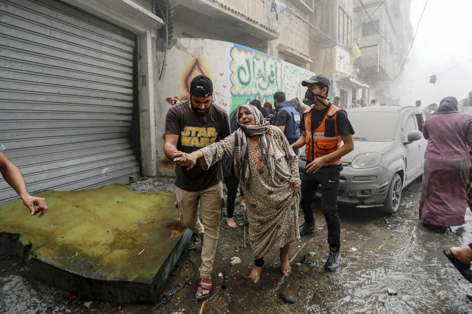 23日、イスラエル軍による空爆があったパレスチナ自治区ガザ市で、避難する女性を助ける人たち（AP＝共同）