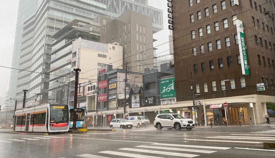 ［写真］朝から激しい雨に見舞われた大阪市内。路面電車は雨に打たれ、車は水しぶきをあげながら走る。左後方は、あべのハルカス＝17日午前9時半ごろ、大阪市阿倍野区で
