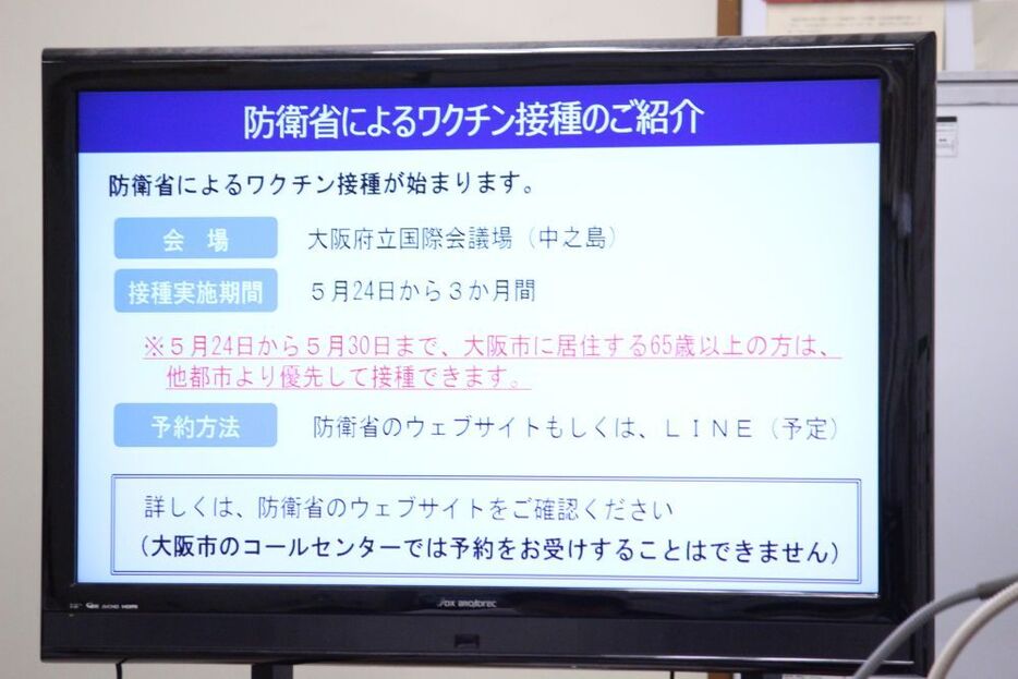 [写真]会見場に掲示された防衛省によるワクチン接種の紹介