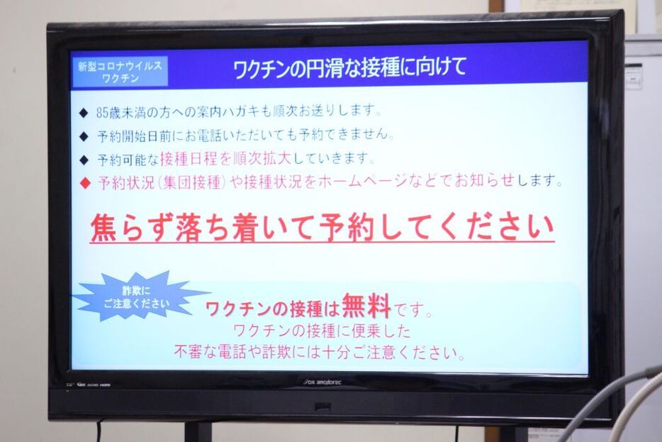 [写真]会見場に掲示されたワクチン予約についての説明