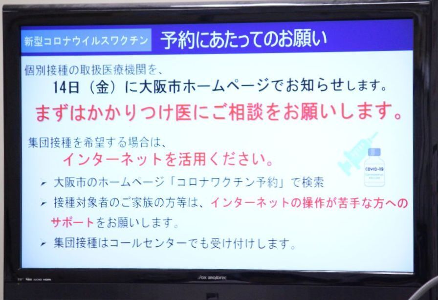 [写真]会見場に掲示されたワクチン予約についての説明