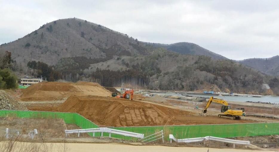 [写真]震災前には160人が暮らしていた女川町の御前浜地区。ここに積み上げられた土砂は、この集落の復旧工事に使うのではなく、市街地造成の土盛などで使われるもので、一時的にこの集落に保管されるために積み上げられている。御前浜地区の高台造成が完成し、地域の人たちが戻れるのは、2016年末の予定