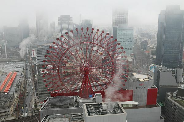 [写真]観覧車の周囲の高層ビルにも雲がかかる＝19日正午ごろ、大阪市北区で