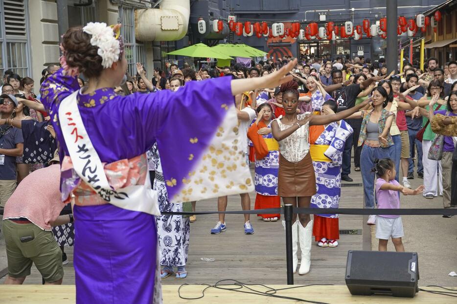 「ミスさんさ踊り」（手前）に踊りを教わる来場者ら＝26日、米ニューヨーク（共同）