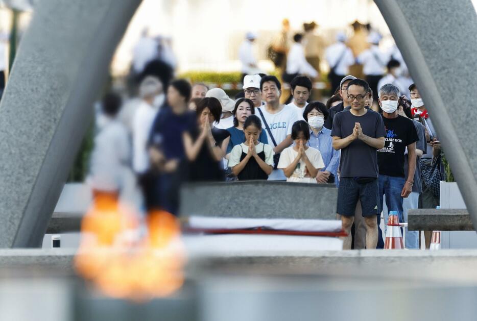 原爆慰霊碑の前で手を合わせる人たち＝6日午前6時10分、広島市の平和記念公園