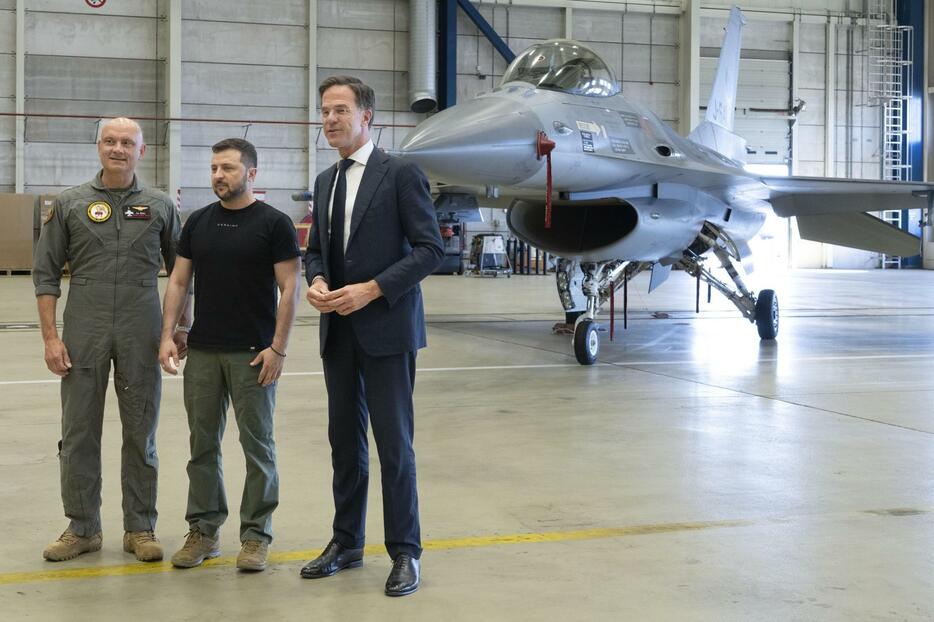 F16戦闘機の前でポーズを取るオランダのルッテ首相（右）とウクライナのゼレンスキー大統領（中央）＝20日、アイントホーフェン（AP＝共同）