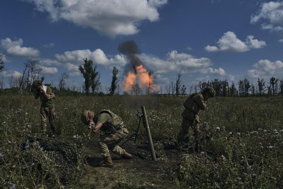12日、ウクライナ東部ドネツク州バフムト付近で迫撃弾を撃つウクライナ兵（AP＝共同）