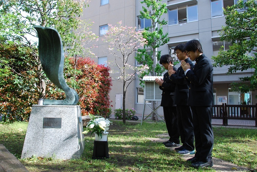 献花後、慰霊碑に向かい手を合わせる現役生徒ら