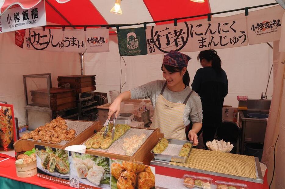 [写真]会場は席が足りないほど多くの人が詰め掛けたので、歩きながら食べられる「にんにくまんじゅう」は人気の一品