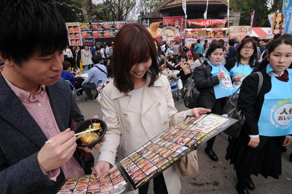 [写真]会場案内パンフレットを見ながら、次は何を食べようか話し合うカップル