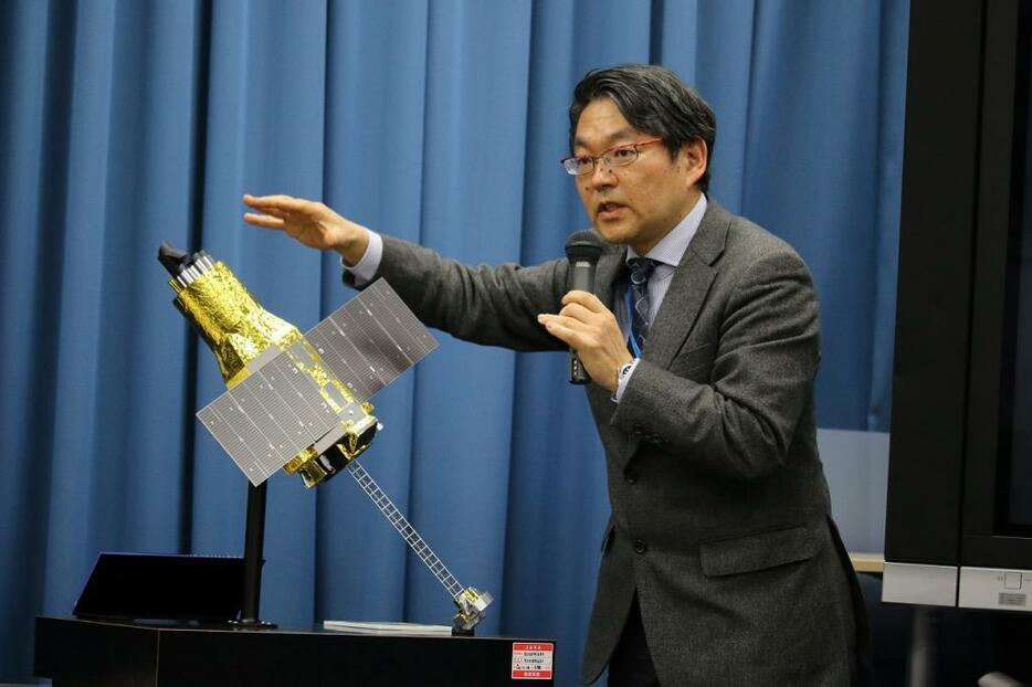 [写真]「ひとみ」の模型を使って機体の回転状況について説明するJAXA宇宙科学プログラムディレクタの久保田孝氏