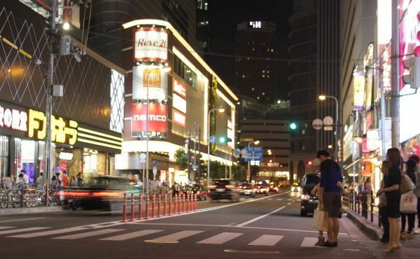 [写真]信号待ちのカップルが「半そで寒いな」と言いながら、大阪マルビルの電光掲示板の表示を眺める＝6日午後8時40分ごろ、大阪市北区角田町で