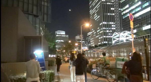 [写真]3年ぶりの天体ショーをじっと見守る通行人ら＝8日午後7時10分ごろ、大阪市北区で