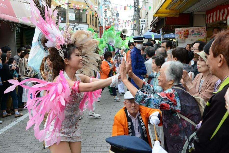 ダンサーとハイタッチする沿道の女性