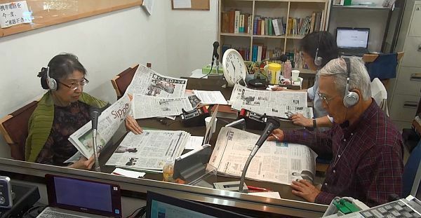 [写真]スタジオでは新聞を何紙も広げ、読み手ボランティアがていねいに記事を読み上げる＝大阪市都島区で