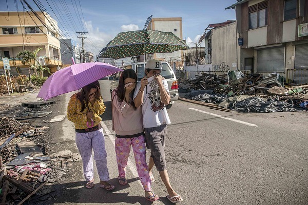 [写真]タクロバン市内を鼻を押さえて歩く人びと。遺体を入れた袋が長く道端に放置されているため、被災地のあちこちに悪臭が立ち込めている(c)Yann Libessart/MSF